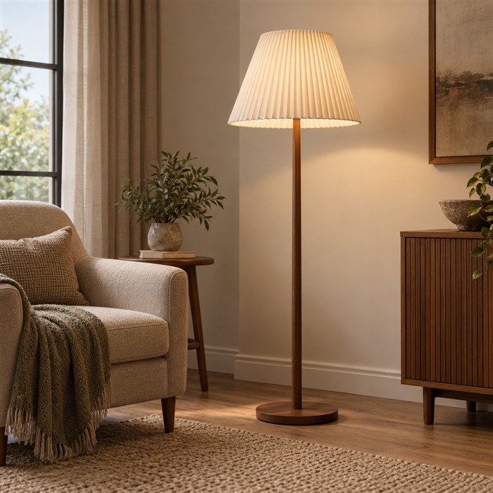 Vloerlamp met een crèmekleurige geplooide stoffen kap naast een beige fauteuil.
