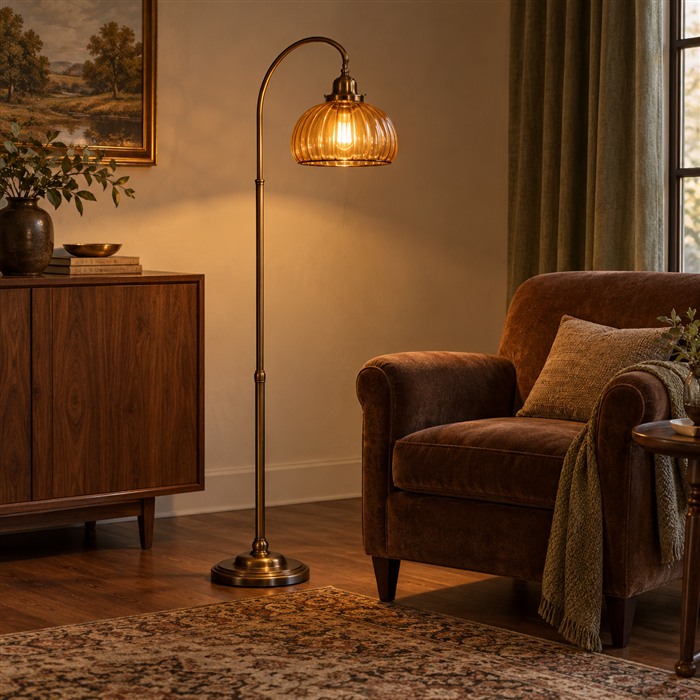 Vloerlamp met een amberkleurige glazen kap naast een bruine fauteuil en een houten kast.