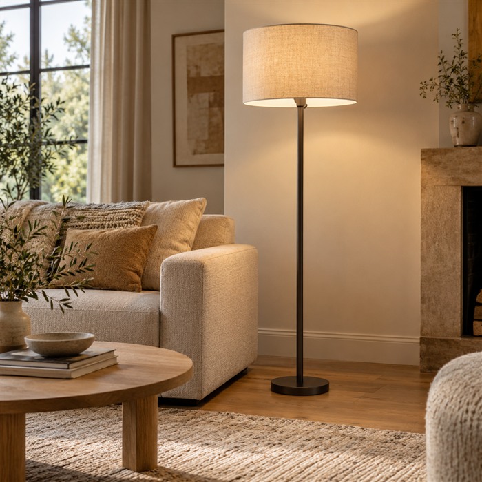 Vloerlamp met een beige stoffen kap naast een bank en een ronde salontafel.